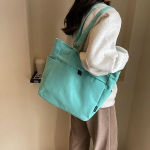 Detail view of mint green canvas tote bag showing side storage pocket and handle