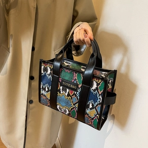 Close-up of stylish faux leather tote bag featuring colorful snake print and black strap