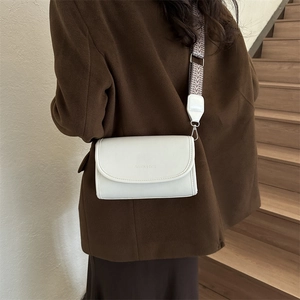 White PU leather crossbody bag with patterned strap shown on a wool coat model