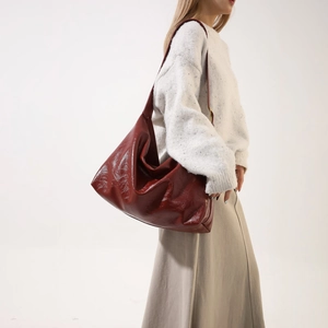 Side view of a large burgundy PU shoulder bag on a model wearing a white sweater