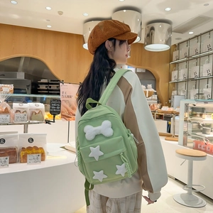 Close-up of light green nylon backpack with plush bone and white star decorations