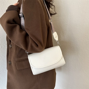 White faux leather crossbody bag detail with woven wide strap and fashion embossed text
