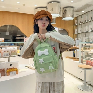 Close-up of a light green nylon mini backpack with plush star and bone charms decoration