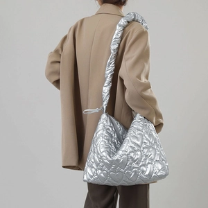 Detail of silver heart-quilted nylon handbag with ruffled strap on stylish shoulder