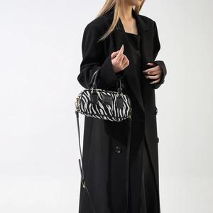 Dettaglio borsa tote in lana zebrata con manici in pelle nera e finiture metalliche oro