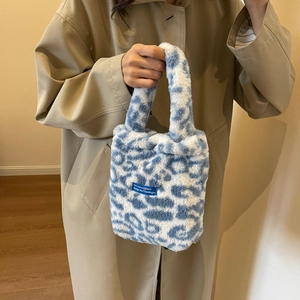 Detail view of plush faux fur handbag with blue and white leopard print and wide handle