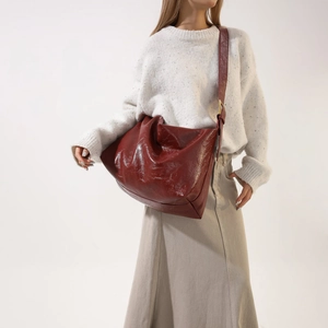 Detail view of large dark red PU leather crossbody bag with soft pleated texture and wide strap