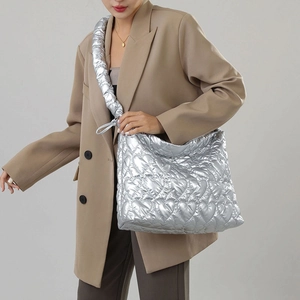 Silver quilted tote bag with heart stitching and wide shoulder strap shown on model
