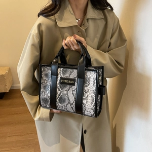 Detail of trendy tote bag with snake skin pattern texture and branded label on coat sleeve