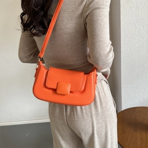 Detail view of the orange matte PU leather shoulder bag with matching strap on a model