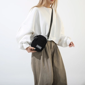Detail view of black corduroy crossbody bag with adjustable nylon shoulder strap