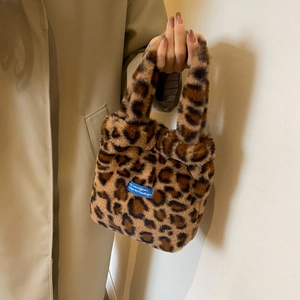Close-up of leopard print plush handbag with blue woven label and soft faux fur texture
