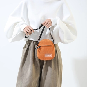 Detail of warm orange corduroy round bag with adjustable strap and fashion patch