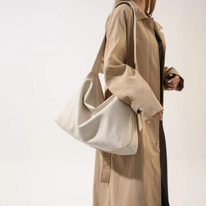 White oversized hobo bag in faux leather texture with matching shoulder strap on a model