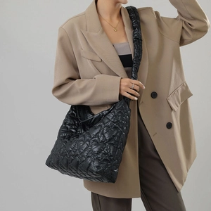 Detail of black quilted nylon shoulder bag featuring 3D heart patterns and ruched strap