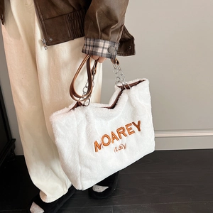 Detail of white plush tote bag with MOAREY embroidery and silver chain handle