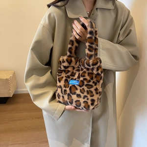 Plush leopard print handbag with blue woven label and soft handles in winter setting