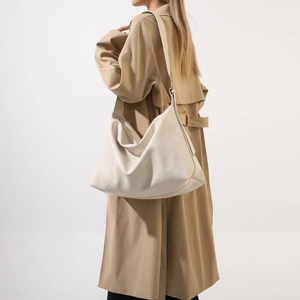 Hobo shoulder bag in creamy white leather texture worn by model in a khaki trench coat