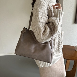 Detail of gray-brown PU leather tote bag showing matte litchi texture and stitching