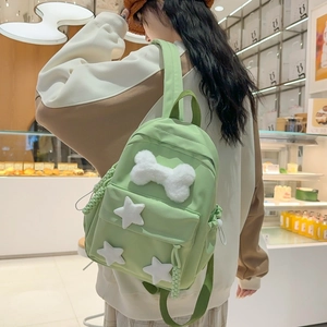 Chic light green nylon backpack with plush bone and star charms on a model in a cafe