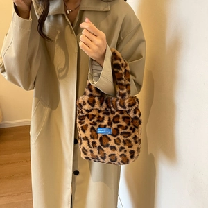 Detail of leopard print faux fur handbag with blue label held by model in trench coat