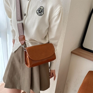 Close-up of brown PU leather bag featuring a colorful geometric woven wide shoulder strap