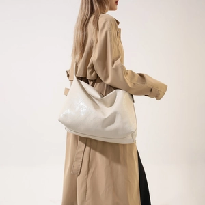 Detail of cream white oversized faux leather shoulder bag with a soft pleated texture