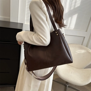 Detail of dark coffee PU leather tote bag with gold rivets and geometric woven strap