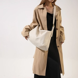 Detail of a large cream crescent shoulder bag featuring soft textured faux leather material