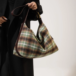 Detail of tartan pattern texture and brown leather strap on hobo shoulder bag