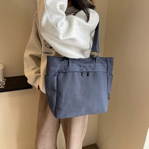 Detail of high-density canvas tote bag featuring side pockets and a fashion woven label