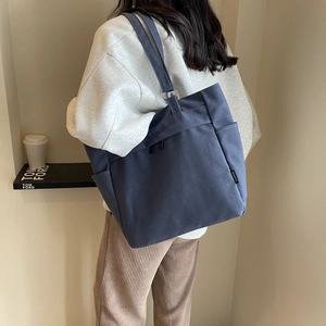Detail of navy blue canvas tote bag side pocket with fashion label on shoulder strap