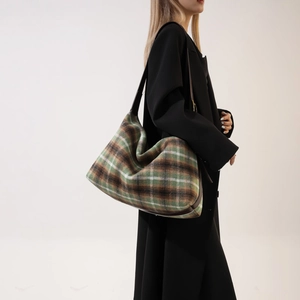 Detail of green plaid wool tote bag showing texture and brown leather shoulder strap