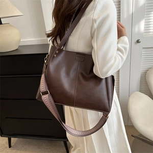 Detail of dark brown PU leather tote bag with braided strap and metal rivets