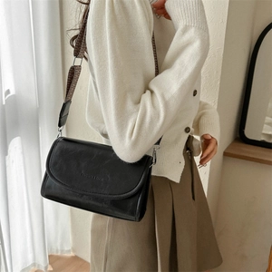 Detail of black PU crossbody bag with vintage texture and wide geometric strap