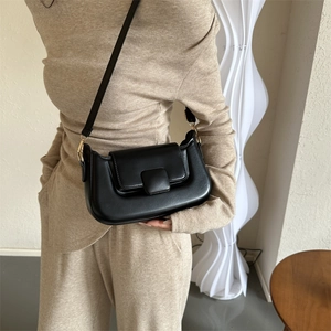 Close-up of a black PU leather crossbody bag with minimalist square buckle on a model