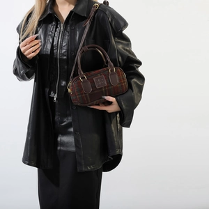 Dettaglio della borsa Boston in lana e pelle indossata con una giacca di pelle nera