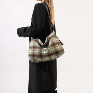 Detail of green plaid wool hobo bag showing thick texture and brown leather strap
