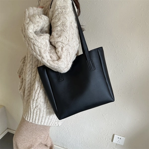 Detail view of black PU leather tote bag with fine texture and long double handles