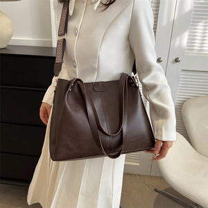 Deep brown matte tote bag with geometric pattern wide strap worn by a model in a room