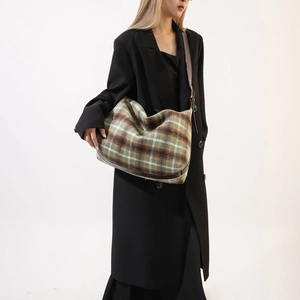 Detail view of large plaid wool blend crossbody bag featuring retro green and brown patterns