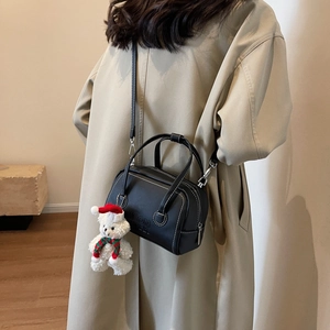 Detail of black leather Boston bag with contrast white stitching and plush bear charm