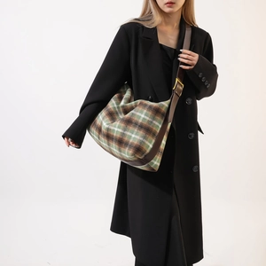 Detail of plaid wool crossbody bag featuring green, brown, and white checkered pattern