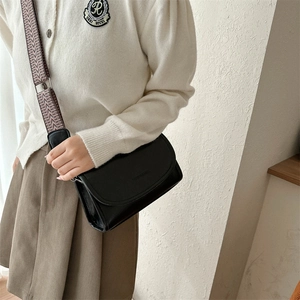 Detail of black PU leather crossbody bag with vintage geometric woven wide strap