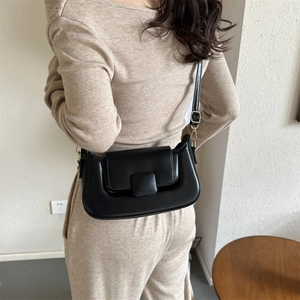 Detail shot of a black PU leather crossbody bag featuring gold hardware on a female model