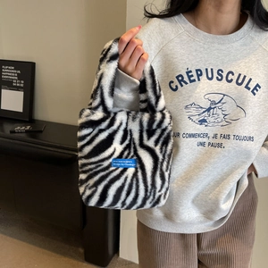 Detail shot of plush faux fur tote bag with black and white zebra pattern and blue label