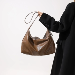 Detail of hobo bag showing the shiny brown synthetic leather texture and shoulder strap