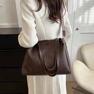 Detail of a dark brown PU leather tote bag with stylish patterned strap on a model