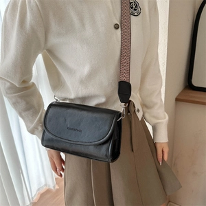 Close-up of black PU leather crossbody bag with ethnic style woven wide shoulder strap