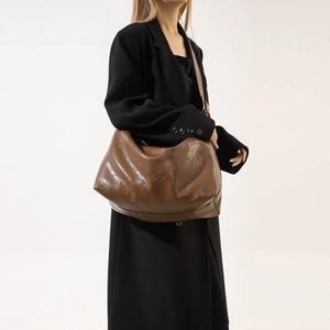 Brown faux leather tote bag with wide strap shown on model for a casual look